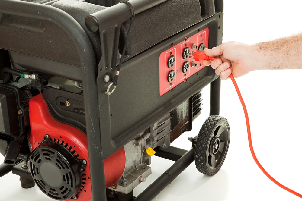 Man's Hand Plugging An Extension Cord into An Emergency Generator - generator installation